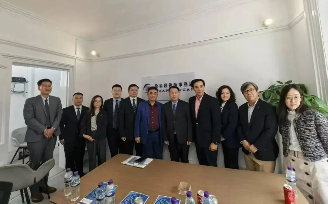 The CIETAC delegation and Duan & Duan lawyers standing in a meeting room in front of the Duan & Duan sign in London
