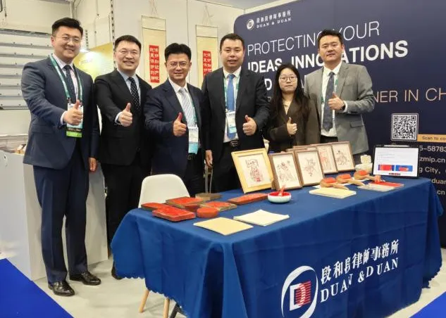 Duan & Duan lawyers at the Duan & Duan booth at INTA 2026, with framed woodblock prints and carved printing blocks on the table