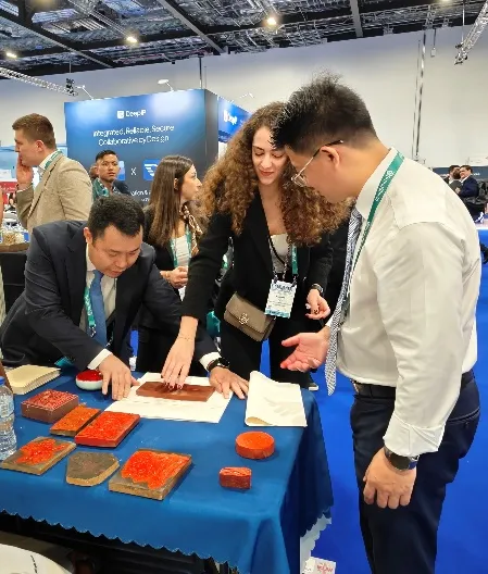 A visitor making a print from a carved woodblock at the Duan & Duan booth, guided by Duan & Duan lawyers