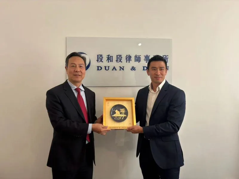 Leon Chua, Partner at Duan & Duan UK LLP, exchanging a commemorative gift with a member of the Xiamen Arbitration Commission delegation in front of the Duan & Duan sign in London